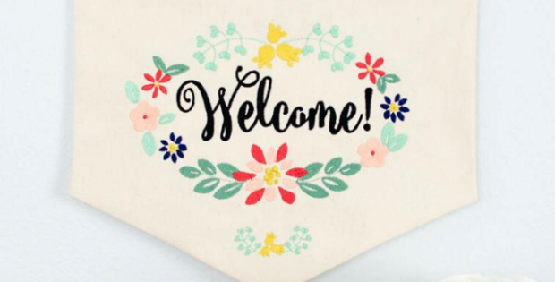 Welcome a new friend or neighbor by adding this free welcome wreath embroidery design to a dishtowel, banner, pillow or flag. #freeembroiderydesign #embroiderydesign